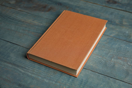 Hardcover book on light blue wooden table. Space for textの写真素材