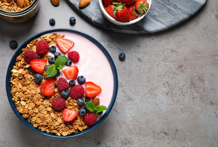 Healthy homemade granola with yogurt on gray table, flat lay. Space for textの写真素材