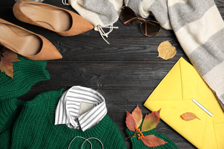Flat lay composition with warm clothes and autumn leaves on black wooden background, space for textの写真素材