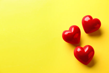Red hearts on yellow background, flat lay. Space for textの写真素材