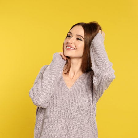 Beautiful young woman in sweater on yellow background. winter seasonの写真素材