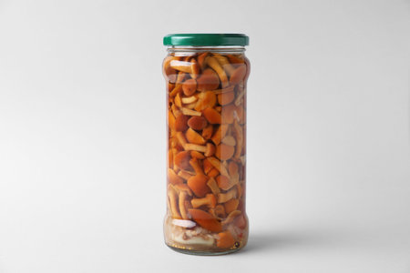 Jar of pickled mushrooms on light gray backgroundの写真素材