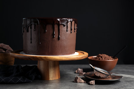 Freshly made delicious chocolate cake on gray table against black backgroundの写真素材