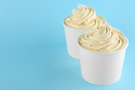 Cups with tasty frozen yogurt on blue background. Space for textの写真素材