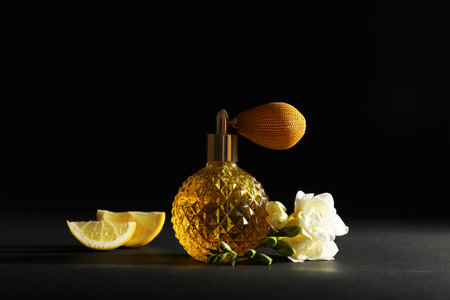 Vintage bottle of perfume, beautiful flower and citrus fruit on black background