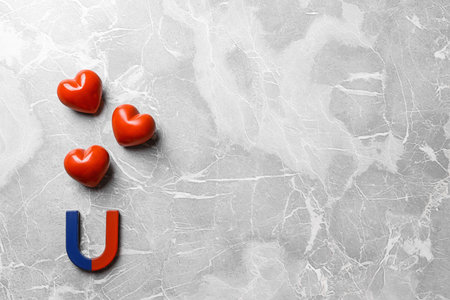 Red and blue horseshoe magnet with hearts on gray marble background, flat lay. Space for textの写真素材