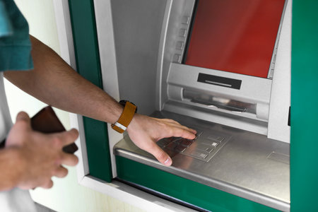 Man entering PIN code on cash machine keypad outdoors, closeupの写真素材