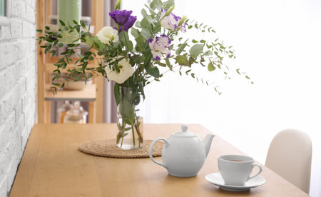 Teapot, cup and flowers on wooden dining table indoors. kitchen interiorの写真素材