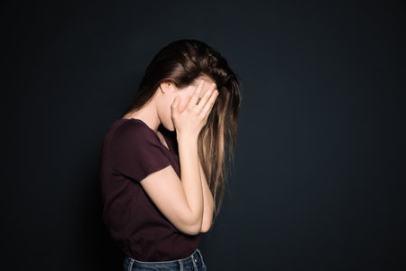 Upset young woman crying against dark background. Space for textの写真素材