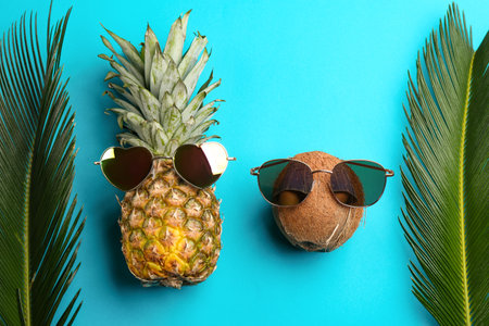 Pineapple and coconut with sunglasses on blue background, flat layの写真素材