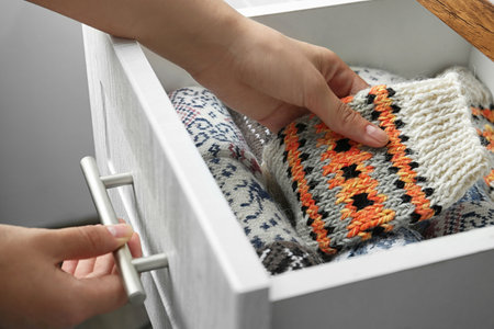 Woman taking warm knitted socks out of drawer, closeup