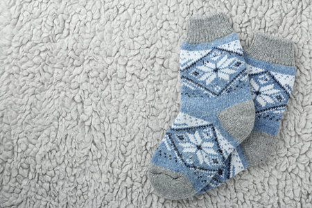 Knitted socks on gray fur background, flat lay. Space for textの写真素材