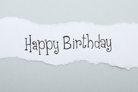 Sheet of paper with words HAPPY BIRTHDAY on light gray background, top viewの写真素材
