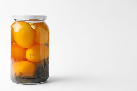 Jar of pickled yellow tomatoes on white backgroundの写真素材