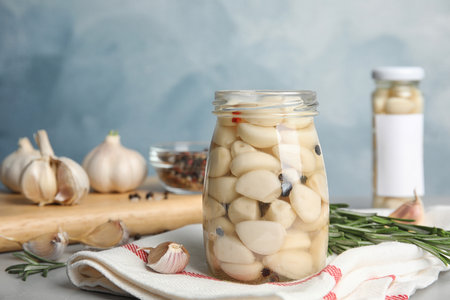 Composition with jar of pickled garlic on gray table against blue backgroundの写真素材