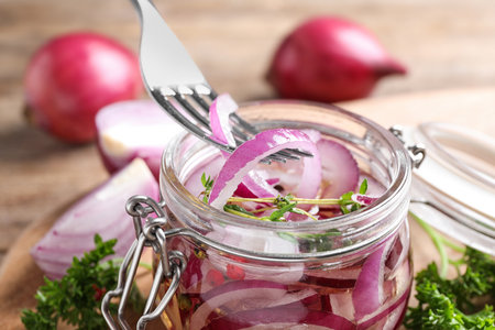 Fork with slices of pickled onion over jar on table, closeupの写真素材