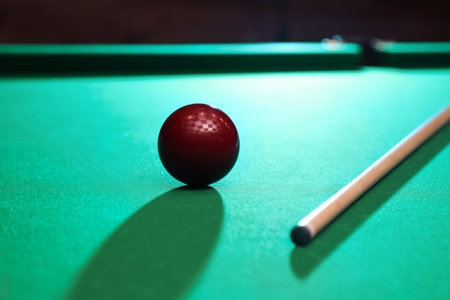 Red billiard ball and cue on tableの写真素材