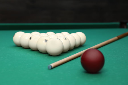 Billiard balls and cue on table indoors