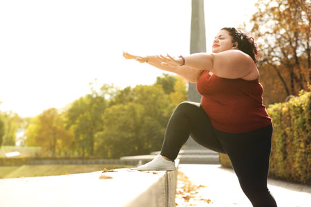 Beautiful overweight woman doing sport exercises in parkの写真素材