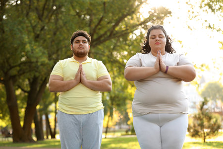 Overweight couple training together in park on sunny dayの写真素材
