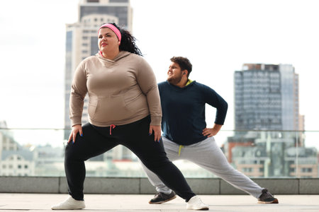 Overweight couple doing sport exercises together outdoorsの写真素材