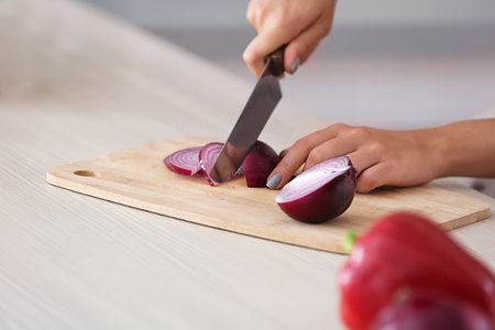 Young woman cutting onion at table, closeupの写真素材