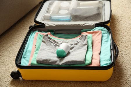 Deodorant in packed suitcase on floor indoorsの写真素材