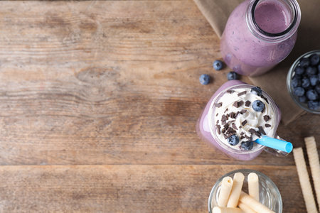 Tasty blueberry milk shake served on wooden table, flat lay. Space for textの写真素材