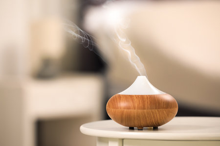 Modern essential oil diffuser on table indoors. Space for textの写真素材