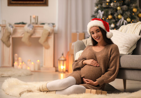Happy pregnant woman with Christmas gift box at home. Expecting babyの写真素材