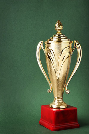 Shiny golden trophy cup on green backgroundの写真素材