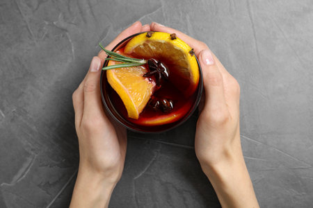 Young woman holding glass with tasty mulled wine at gray table, top viewの写真素材