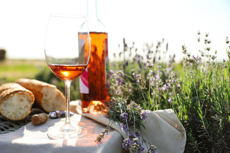 Composition with glass of wine on wicker table in lavender field. Space for textの写真素材