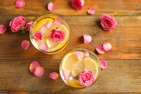 Tasty refreshing lemon drink with roses on wooden table, flat layの写真素材