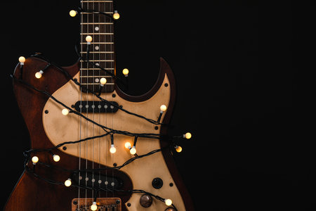 Guitar with golden lights on black background, space for text. christmas musicの写真素材
