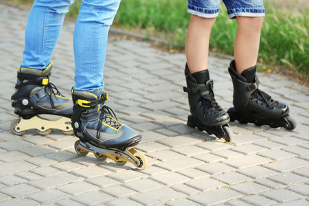 Father and son roller skating in park, closeup of legs