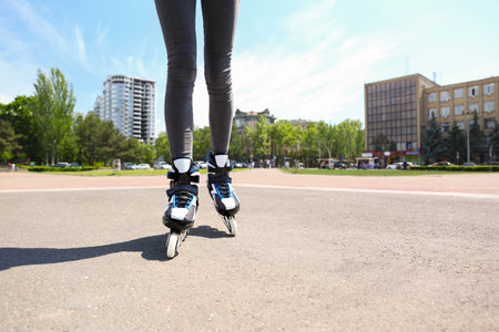 Woman with modern inline roller skates in city park, closeupの写真素材