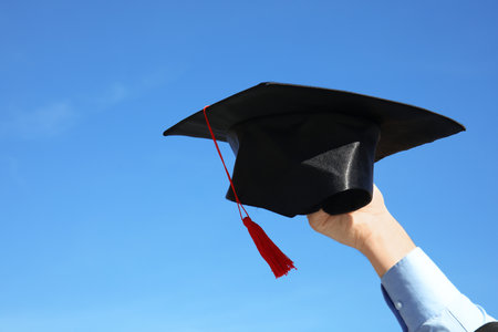 Student with graduation hat and blue sky on background, closeupの写真素材