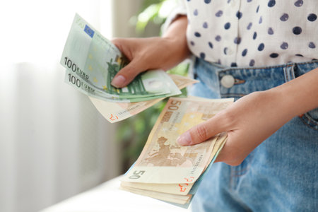 Woman with Euro banknotes in room, closeup