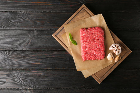 Fresh raw minced meat on black wooden table, top view. Space for text