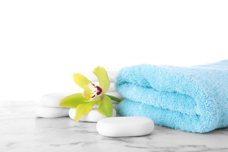 Fresh towel, spa stones and exotic flower on marble table against white backgroundの写真素材