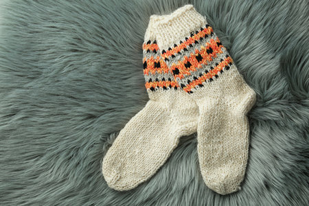 Knitted socks on gray faux fur, flat lay. Space for text