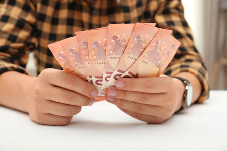 Man with Euro banknotes at table indoors, closeupの写真素材
