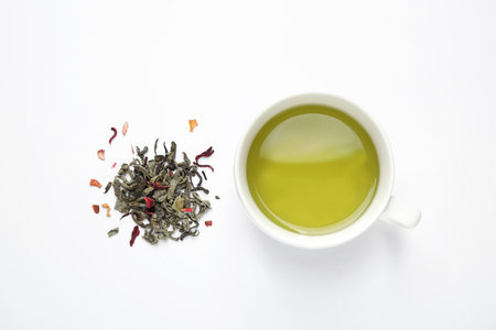 Green tea leaves and cup of hot beverage on white background, flat layの写真素材