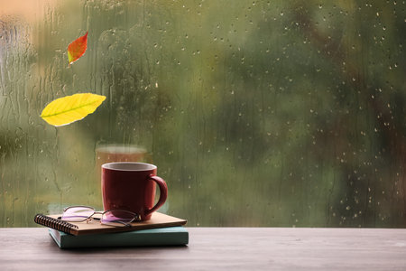Composition with cup of drink and autumn leaf on windowsill, space for text. rainy weatherの写真素材