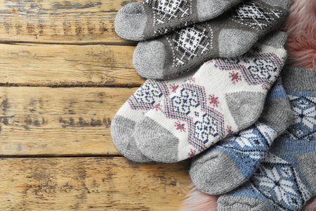 Knitted socks and pink faux fur on wooden table. Space for textの写真素材