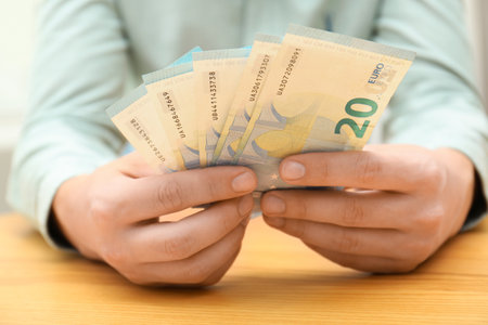 Man with Euro banknotes at table, closeupの写真素材