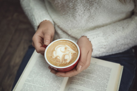 Woman with cup of coffee reading book at home, closeupの写真素材