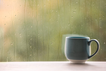 Cup of drink on windowsill, space for text. rainy weatherの写真素材