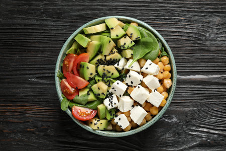 Delicious avocado salad with feta cheese on black wooden table, top viewの写真素材